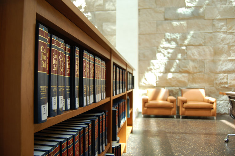  A bookshelf lined with books and two orange chairs in the background.