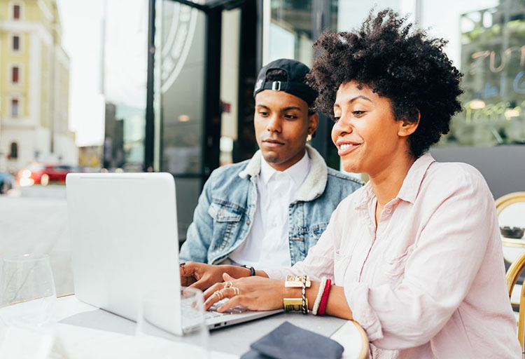  Two people looking at the laptop screen while one person is typing on the keyboard.