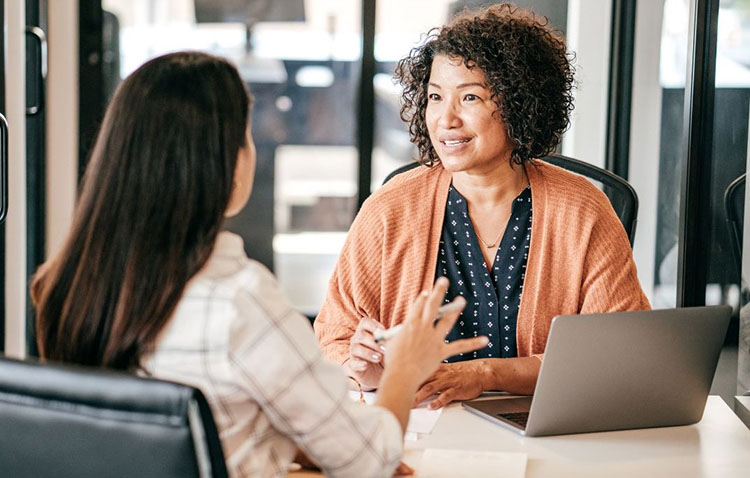 Two women sitting across from each other having a conversation.